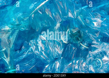Crushed plastic bottles on blue background. A symbol of environmental pollution and recycling challenges and successes Stock Photo