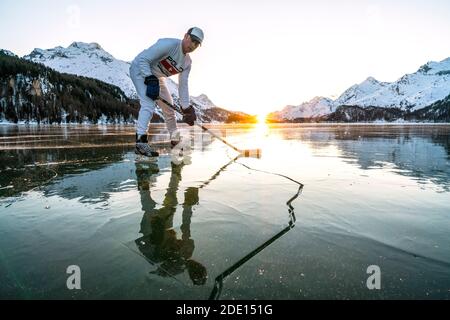 Front view of ice hockey player on cracked surface of frozen Lake Sils, Engadine, Graubunden canton, Switzerland, Europe Stock Photo