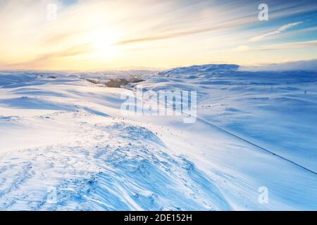 Aerial view of empty road across mountains covered with snow lit by sunrise, Sennalandet, Alta, Troms og Finnmark, Arctic, Norway Stock Photo
