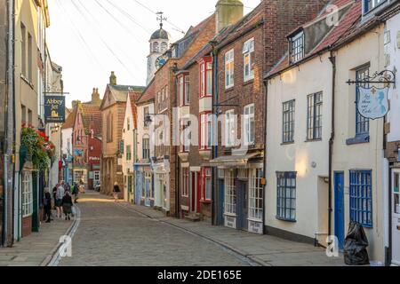 View of shops on traditional cobbled street in historic town centre, Whitby, Yorkshire, England, United Kingdom, Europe Stock Photo