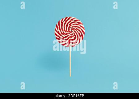 Colorful lolipop on blue background, wooden stick, red and white spiral, childhood sweets, Christmas concept Stock Photo