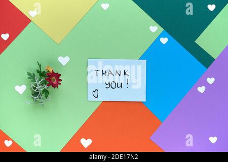International Thank you day. Greeting card with female hand holding envelope with heart shape and flowers. Thank you handwriting on card. Concept flat Stock Photo