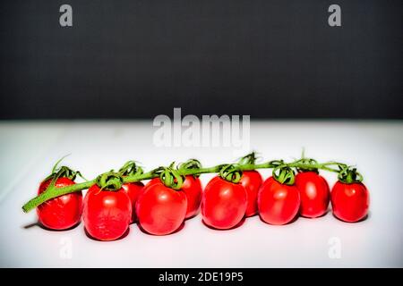 Cherry tomatoes on white table and black background Stock Photo