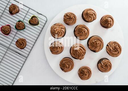 Many chocolate cupcakes decorated with chocolate frosting closeup on kitchen table directly from above Stock Photo