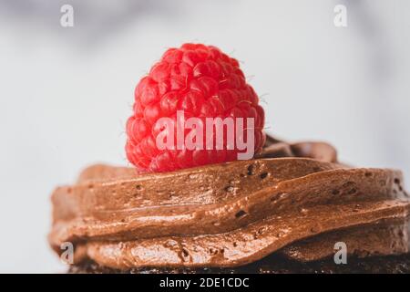 Chocolate buttercream frosting and raspberry on top, extremely close up. Chocolate cupcake decorated with fresh berries Stock Photo
