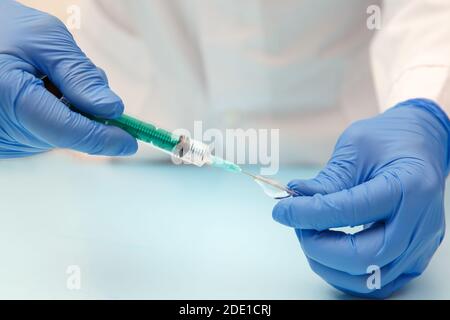 Doctor in protective gloves draws medicine into a medical syringe Stock Photo