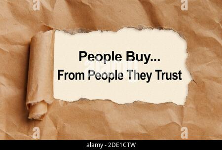 Text People buy from people they trust, appearing from tattered craft paper Stock Photo