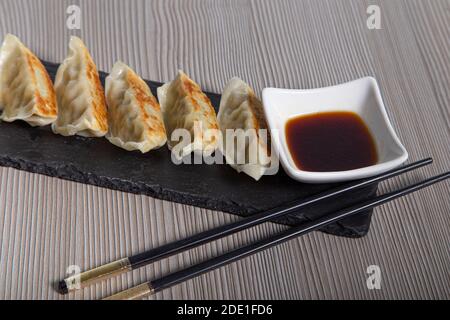 Chicken gyozas. Served on slate dinnerware with chopsticks and soy sauce. Asian dinner Stock Photo