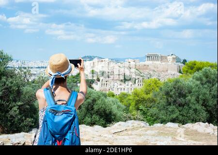 Young tourist girl takes photos of Acropolis from Philoppapos hill, Athens, Greece Stock Photo