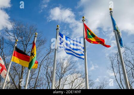 Flag of Greece Waving Proudly Amongst Other Flags Outside United Nations Headquarters in New York City, USA. Low Angle View in a Sunny Day of Winter Stock Photo