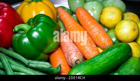 Selective focus of carrots, green bell pepper, lemons on a plate with assorted vegetables Stock Photo