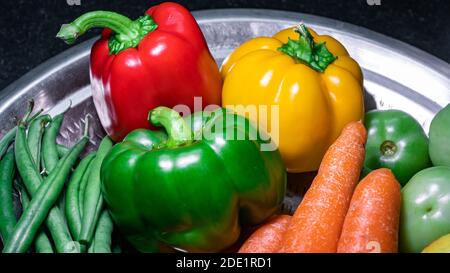 Close up of green bell pepper, red bell pepper, yellow bell pepper on a stainless steel plate Stock Photo