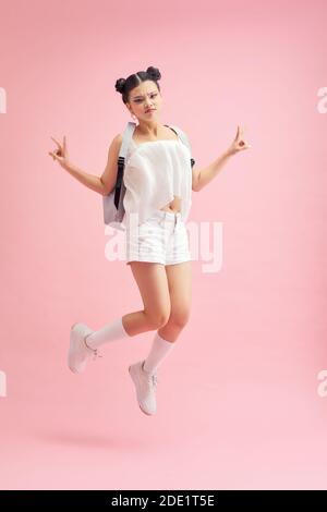 Full length profile photo of funny student lady jumping high showing v-sign symbols wear bag isolated pink color background Stock Photo