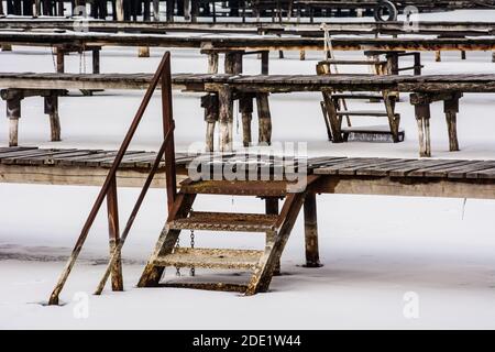 Wooden piers on the frozen lake.A port without boats.Rhythm of horizontally running piers and diagonal steps. Stock Photo