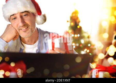 Self-absorbed man looking at a christmas present with wish. Front view. Horizontal composition. Stock Photo