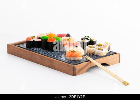 Close up of assorted maki, nigiri and uramaki with chopsticks on a wooden tray on a light background. Sushi and healthy food concept. Stock Photo