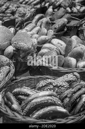 Black & white image of an assortment of breads and pretzels in baskets for sale in a bakery Stock Photo