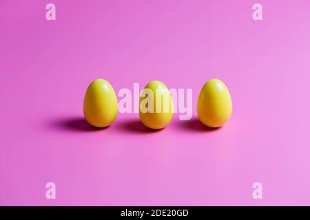 Three Yellow Plastic Easter Eggs on pink background. Stock Photo