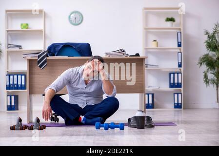 Handsome male employee doing exercises in the office Stock Photo