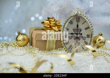 old roman clock in the snow with gift boxes toys on the christmas tree on bokeh background for New Year Stock Photo