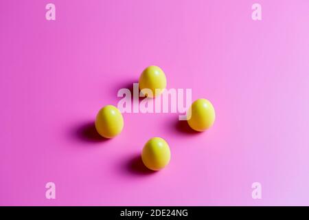 Four Yellow Plastic Easter Eggs on pink background. Stock Photo