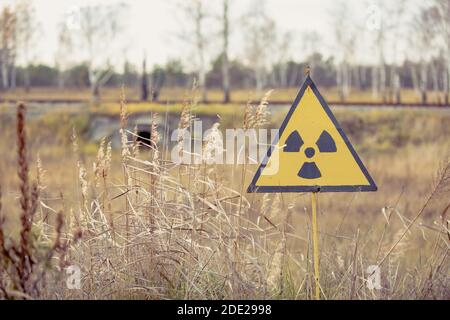Ionizing Radiation sign next to Red Forest in Chernobyl Nuclear Power Plant Zone of Alienation, Ukraine Stock Photo