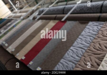 samples of carpets of different colors hung in a textile store, blurred and defocused Stock Photo