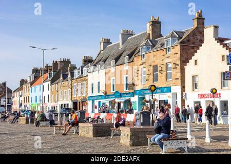 People sat outside the Anstruther Fish bar on the harbour in the scottish coastal port of Anstruther Fife Scotland East Neuk of Fife UK GB Europe Stock Photo