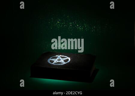 Black magic book on the dark green background Stock Photo
