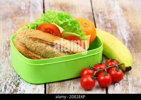 Healthy school lunch box containing brown cheese roll, cherry tomatoes and banana Stock Photo