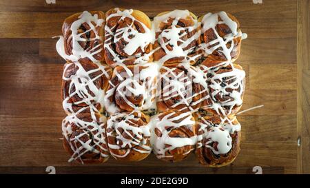 A closeup shot of glazed cinnamon buns on a wooden table Stock Photo