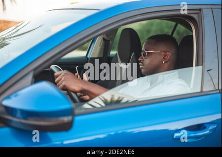 Black entrepreneur using his phone while driving Stock Photo