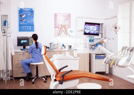 Stomatology office with modern equipment and nurse wearing blue uniform working on computer. Stock Photo