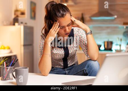 Stressed woman working overtime feels eye fatique after computer work late at night. Employee using modern technology at midnight doing overtime for job, business, busy, career, network, lifestyle. Stock Photo