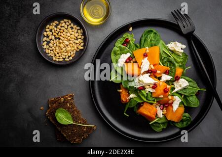 Salad with roasted pumpkin, cheese, spinach, Pine nuts and seasonings on dark background, top view Stock Photo