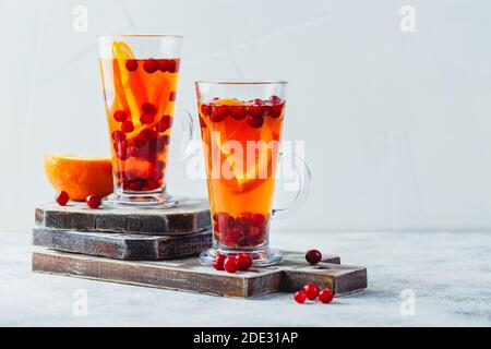 Hot tea with orange slices and cranberries in glass tall glasses. Hot drinks for winter and Christmas. Place for text Stock Photo