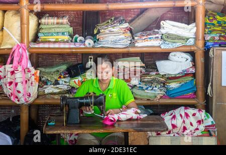 A woman using a sewing machine making bags at a souvenir shop in Bohol, Philippines Stock Photo