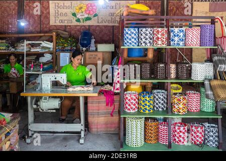 A woman using a sewing machine making bags at a souvenir shop in Bohol, Philippines Stock Photo