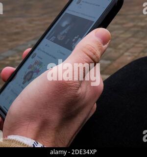 London UK, November 28 2020, Man Holding A Mobile Smart Phone Outside Keeping In Touch With Cyber Life Stock Photo