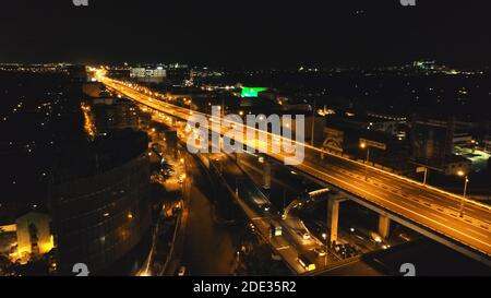 Closeup night traffic highway with driving cars, vans, trucks aerial view. Urban cityscape of Philippines metropolis of Manila close up. Modern buildings with bright illuminated road on bridge Stock Photo