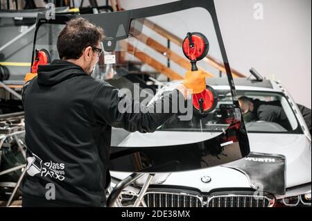 Automobile technician worker replacing windscreen or windshield of a car in auto service station garage. High quality photo Stock Photo