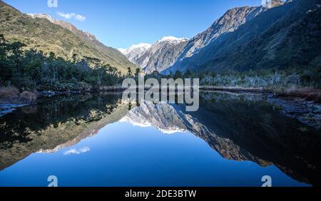 Lake Matheson providing stunning reflections of New Zealand's highest peaks - Aoraki (Mount Cook) and Mount Tasman. Stock Photo