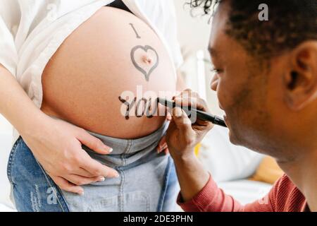 Husband drawing the phrase I love you on the belly of his pregnant wife. Parenthood concept Stock Photo
