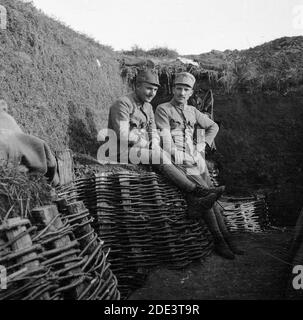 Austro-Hungarian army during the First World War. Two resting soldiers, one of them smiling, in Austrian uniforms sitting in a trench witch sides reinforced by basketwork. Uncertain exact date and location. Stock Photo