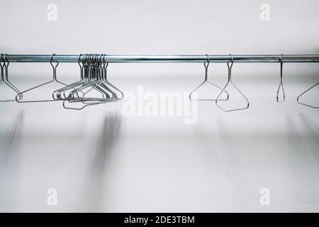 Metal Wire Clothes and Coat Hangers in Closet on White Background Stock Photo