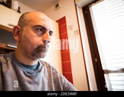 Work from home: portrait of a caucasian man focused on work.The gaze moves on the monitor,the reflection of the changing screen light is recognizable Stock Photo