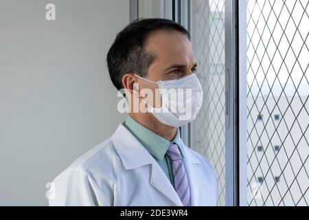 44 year old doctor, smiling, in a white coat and tie, looking at the camera. Stock Photo