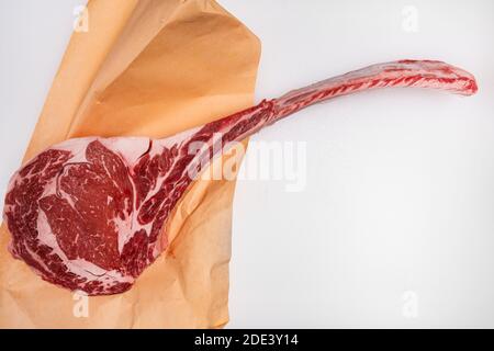 Freshly cut tomahawk ribeye steak with butcher's paper on a meat counter Stock Photo