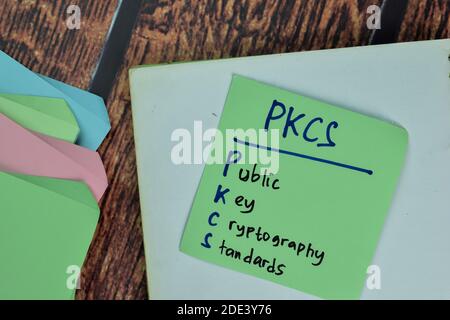 PKCS - Public Key Cryptography Standards write on sticky notes isolated on Wooden Table. Stock Photo
