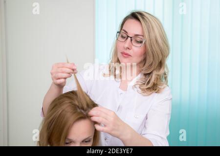 Consultation with a dermatologist. A trichologist examines the hair of a woman Stock Photo